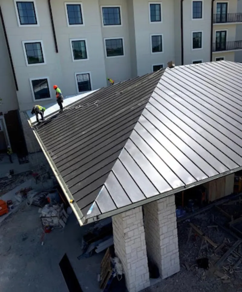 Crew installing standing seam metal roof panels on a commercial project in Golden Gate